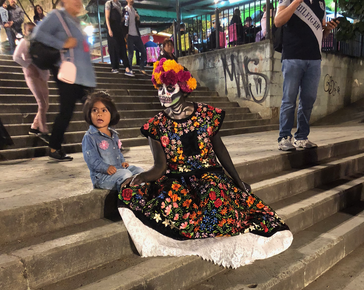 Little girl on steps of Cathedral and woman in costume for Dia de Muertos