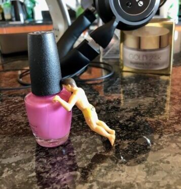 Miniature toy man doing push-ups on nail polish bottle